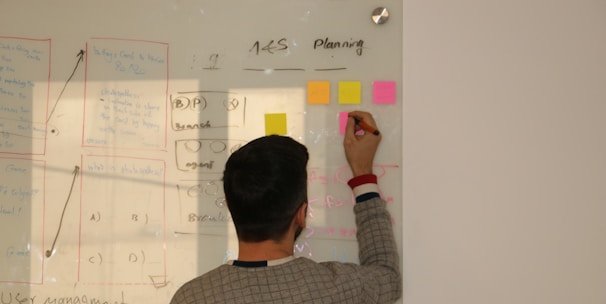 Close-up of hands sketching innovation concepts and AI diagrams on a transparent board.