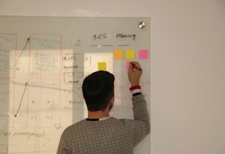 Close-up of hands sketching innovation concepts and AI diagrams on a transparent board.