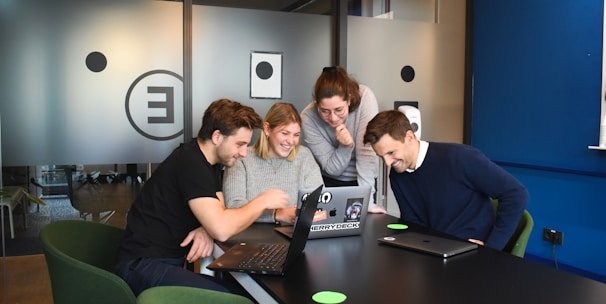 A diverse group of international researchers collaborating over laptops and documents in a bright modern lab.