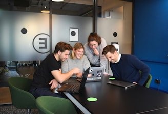 A diverse group of international researchers collaborating over laptops and documents in a bright modern lab.