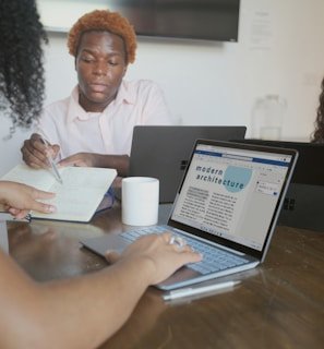 Researchers collaborating around a table filled with laptops and notes during an IFIP CAI workshop.